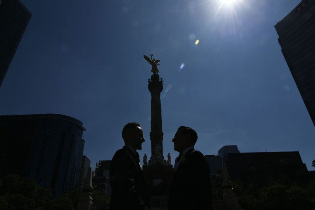 Two grooms facing one another with an angel above them