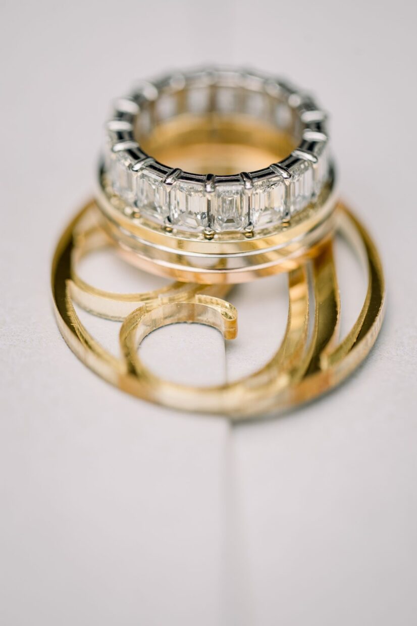 Wedding ring on top of acrylic gold monogram on wedding invitation