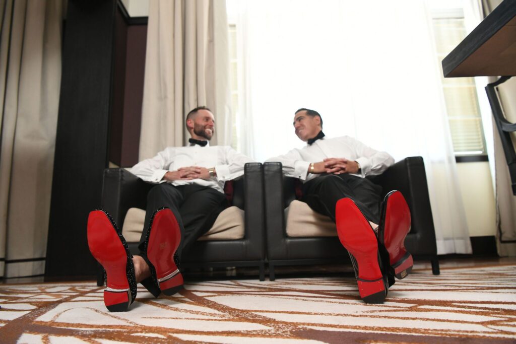 Two grooms wearing red bottom dress shoes