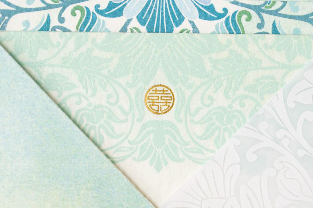 double happiness symbol on multicultural Vietnamese and Indian invitation in gold foil with mint green and teal details